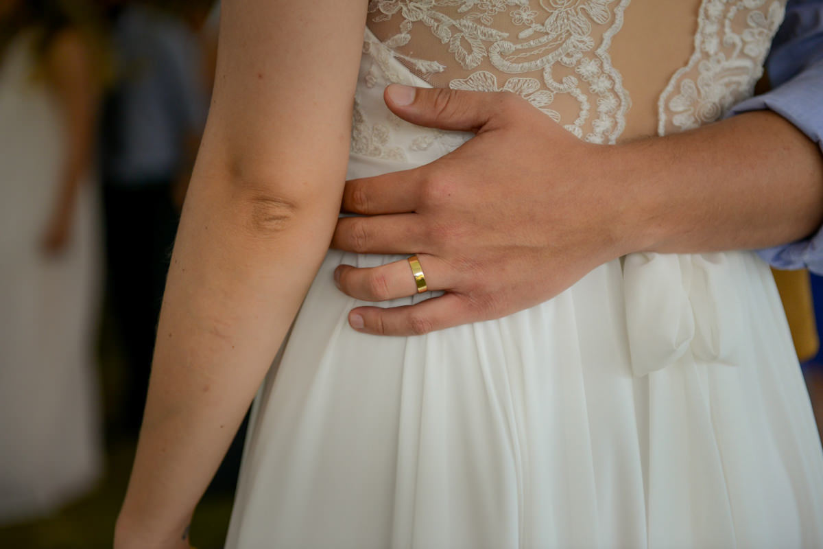 Casamento dos noivos Anna e Bruno ao ar livre em um dia lindo, na região de Curitiba e Campo Largo, fotografado pelo fotógrafo de casamentos Michel Druziki. Detalhe da aliança do noivo segurando a cintura da noiva