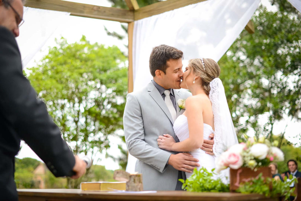Casamento ao ar livre e de dia dos noivos Anny e Rodolfo fotografado pelo melhor fotógrafo de Campo Largo e região de Curitiba, Michel Druziki. Noivos se beijando no altar