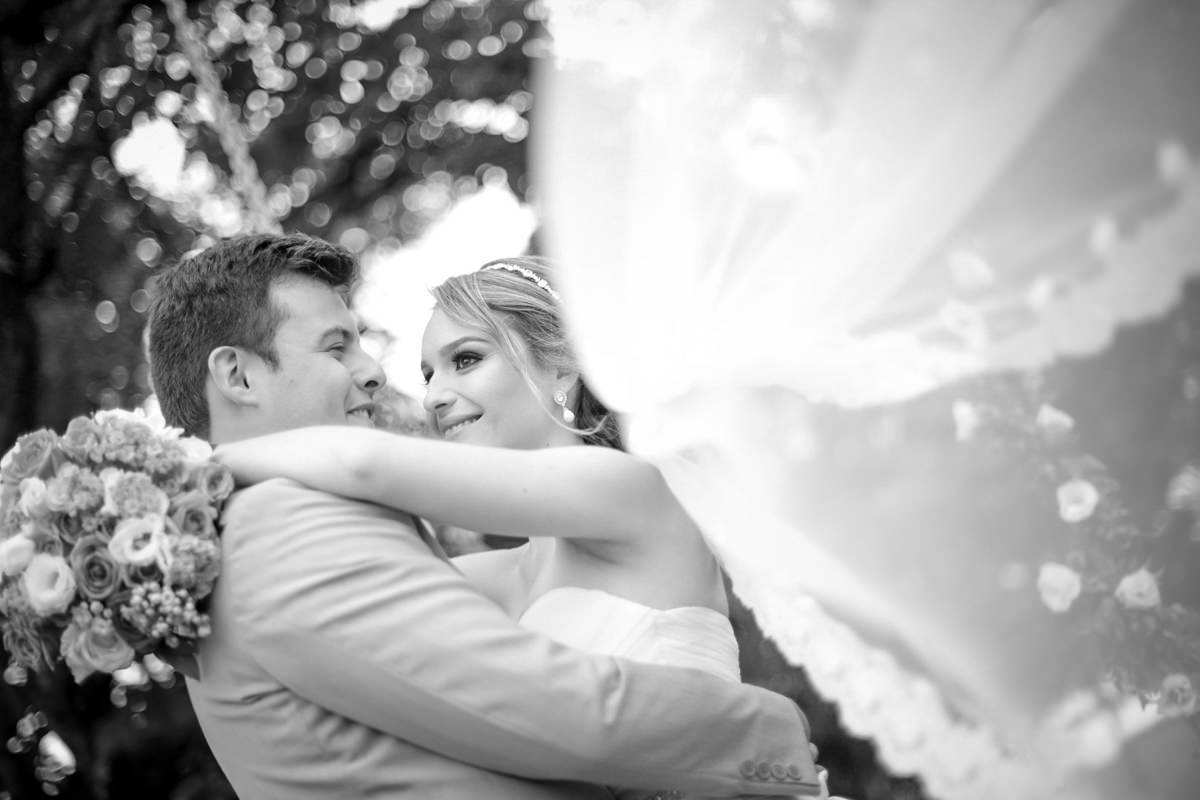 Casamento ao ar livre e de dia dos noivos Anny e Rodolfo fotografado pelo melhor fotógrafo de Campo Largo e região de Curitiba, Michel Druziki. Noivos abraçados e véu da noiva voando