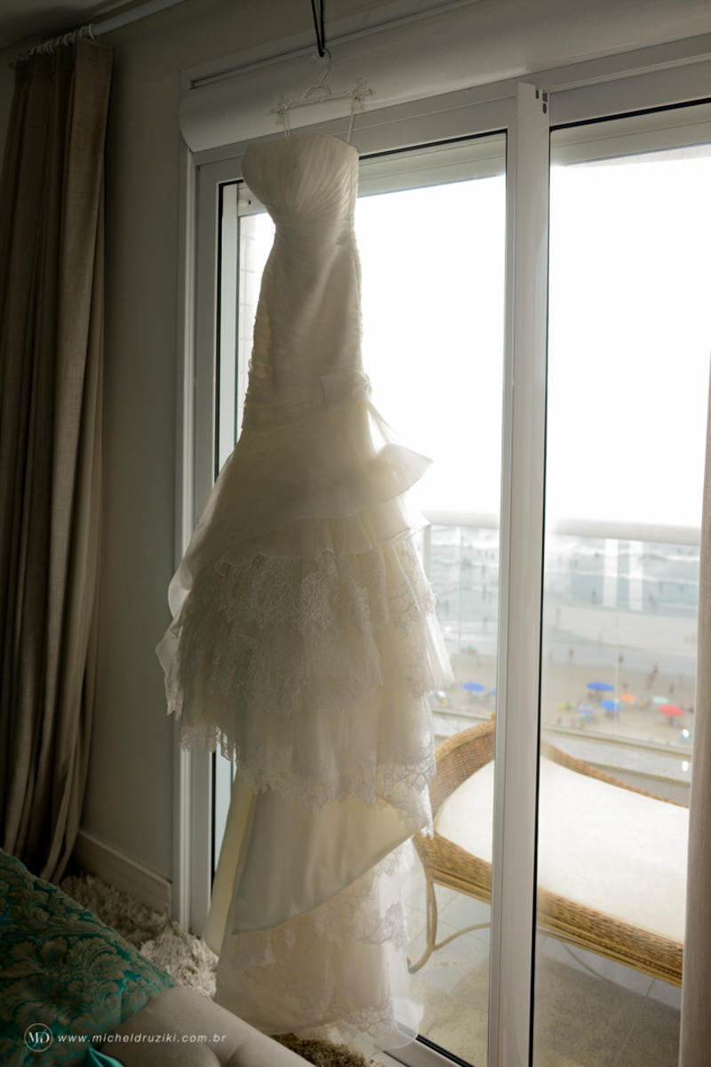 Casamento na praia do casal Dani e André fotografado pelo melhor fotógrafo de casamentos e ensaios de campo largo e Curitiba, Michel Druziki. Vestido da noiva pendurado na janela em frente à praia