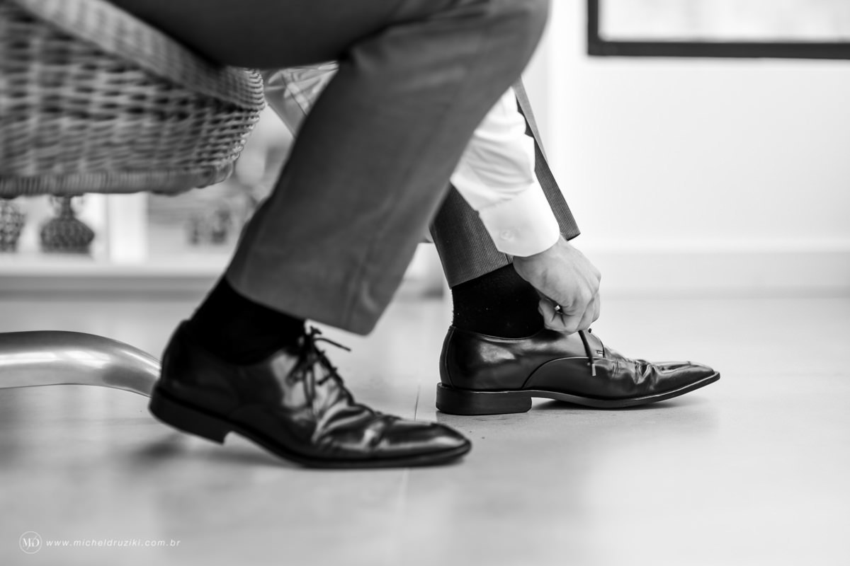 Casamento na praia do casal Dani e André fotografado pelo melhor fotógrafo de casamentos e ensaios de campo largo e Curitiba, Michel Druziki. Noivo amarrando os sapatos