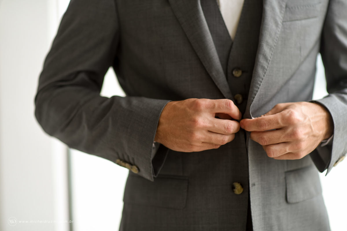 Casamento na praia do casal Dani e André fotografado pelo melhor fotógrafo de casamentos e ensaios de campo largo e Curitiba, Michel Druziki. Noivo abotoando o terno