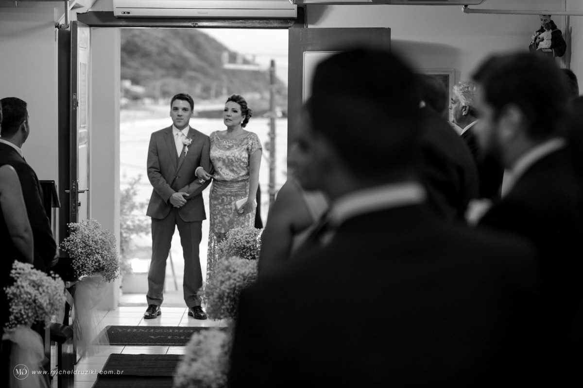 Casamento na praia do casal Dani e André fotografado pelo melhor fotógrafo de casamentos e ensaios de campo largo e Curitiba, Michel Druziki. Noivo entrando na igreja com a mãe 