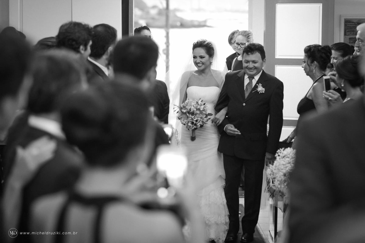 Casamento na praia do casal Dani e André fotografado pelo melhor fotógrafo de casamentos e ensaios de campo largo e Curitiba, Michel Druziki. Noiva entrando na igreja acompanhada do pai