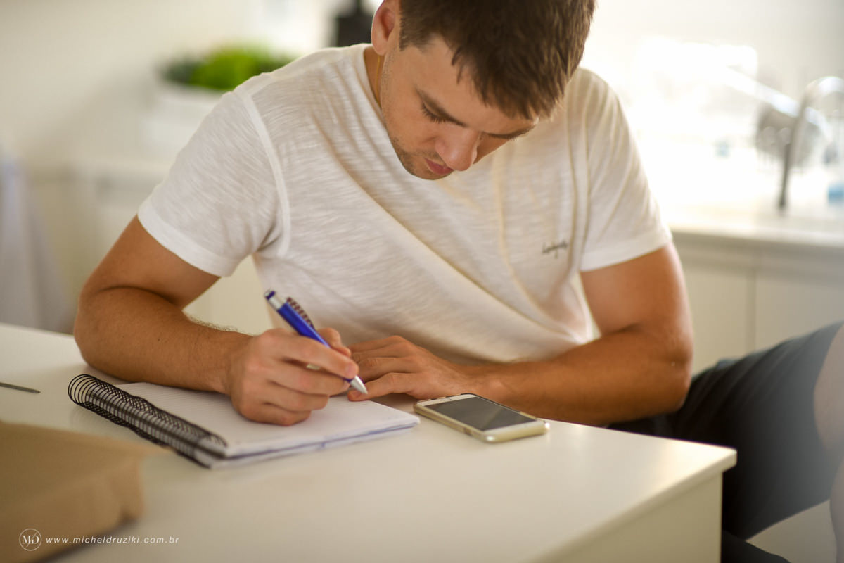 Casamento na praia do casal Dani e André fotografado pelo melhor fotógrafo de casamentos e ensaios de campo largo e Curitiba, Michel Druziki. Noivo escrevendo carta para noiva