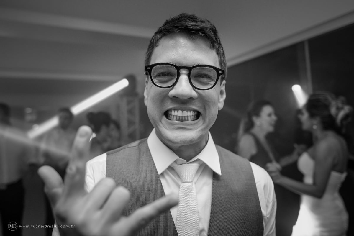 Casamento na praia do casal Dani e André fotografado pelo melhor fotógrafo de casamentos e ensaios de campo largo e Curitiba, Michel Druziki. Noivo com óculos fazendo careta