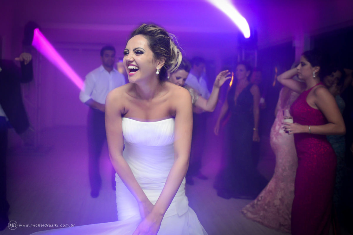 Casamento na praia do casal Dani e André fotografado pelo melhor fotógrafo de casamentos e ensaios de campo largo e Curitiba, Michel Druziki. Noiva dando risada na festa de casamento