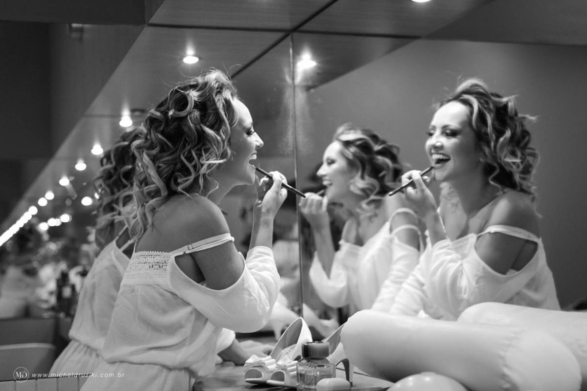 Casamento na praia do casal Dani e André fotografado pelo melhor fotógrafo de casamentos e ensaios de campo largo e Curitiba, Michel Druziki. Noiva passando batom e sorrindo