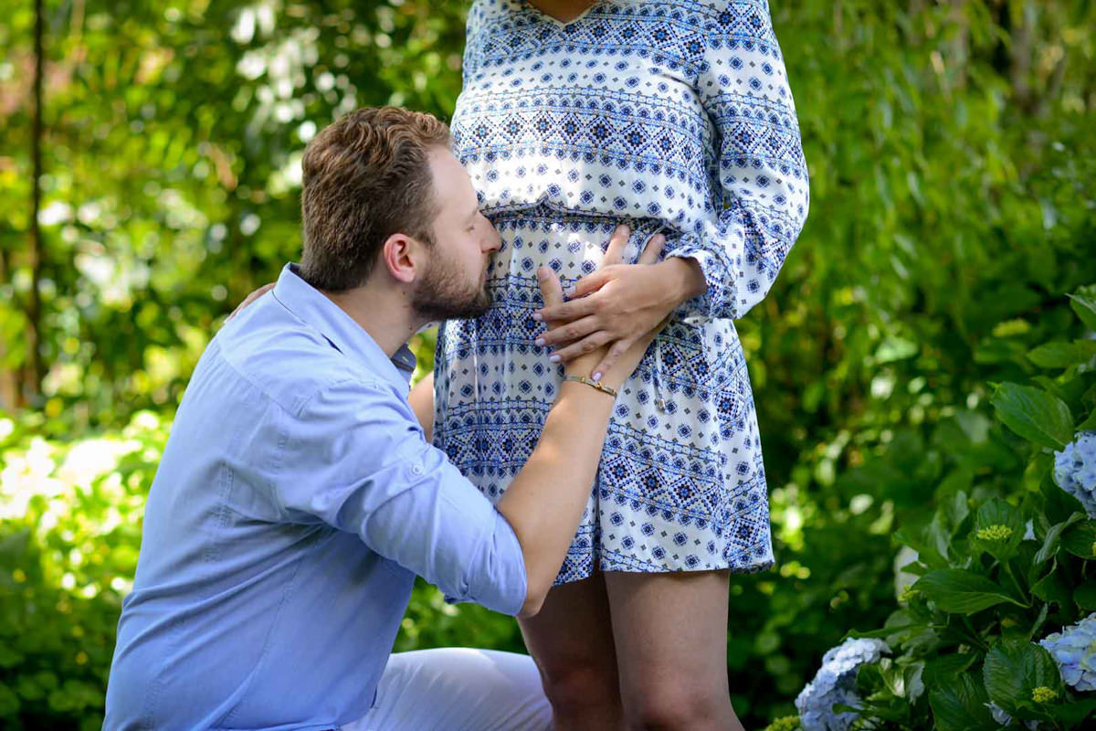 Ensaio de casal gestante em casa com cachorro fotografado pelo melhor fotógrafo de casamentos e ensaios de campo largo e Curitiba, Michel Druziki. Noivo dando beijo na barriga da noiva grávida