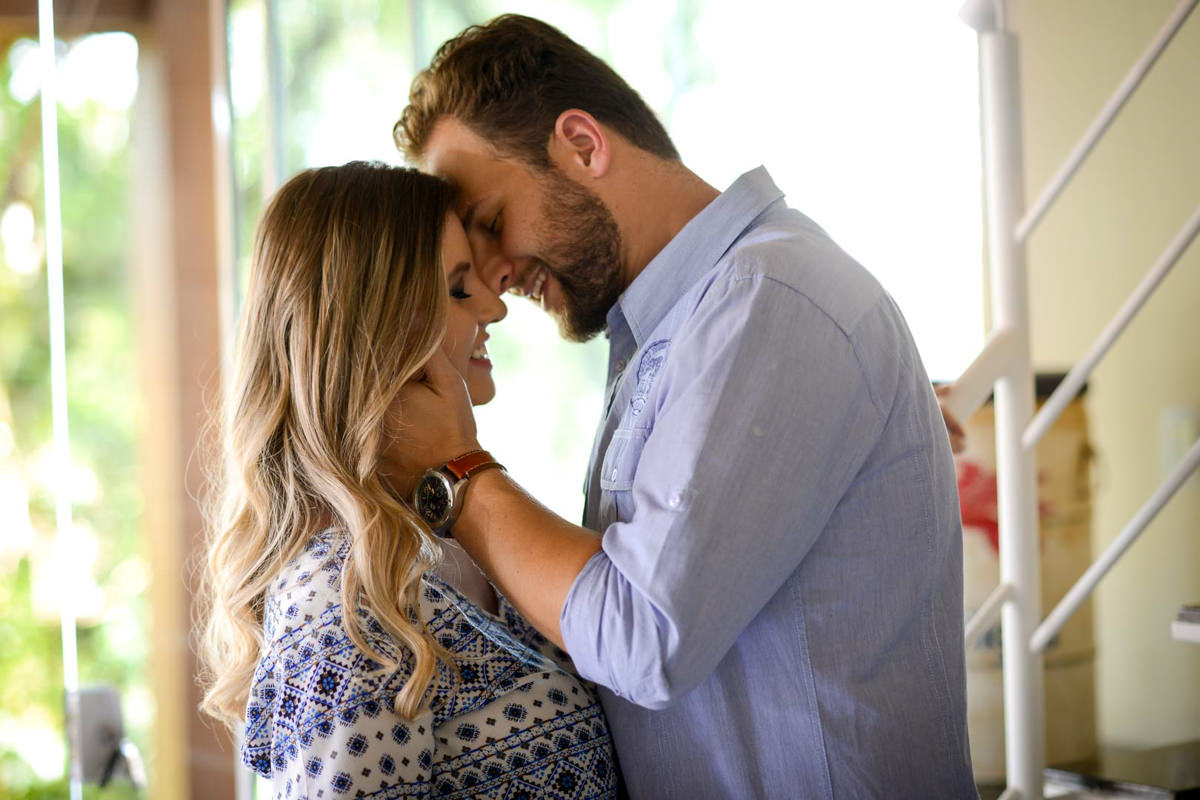 Ensaio de casal gestante em casa com cachorro fotografado pelo melhor fotógrafo de casamentos e ensaios de campo largo e Curitiba, Michel Druziki. Noivos com  o rosto encostado e sorrindo