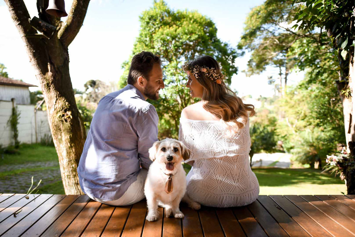 Ensaio de casal gestante em casa com cachorro fotografado pelo melhor fotógrafo de casamentos e ensaios de campo largo e Curitiba, Michel Druziki. Noiva com tiara de flores. Noivos de costas e cachorrinho no meio