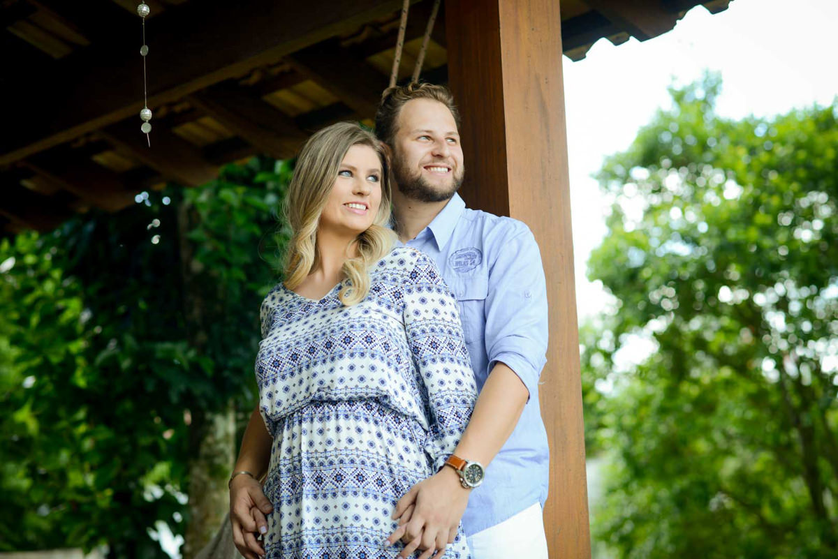 Ensaio de casal gestante em casa com cachorro fotografado pelo melhor fotógrafo de casamentos e ensaios de campo largo e Curitiba, Michel Druziki. Casal abraçado e olhando para a mesma direção