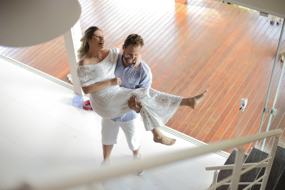 Ensaio de casal gestante em casa com cachorro fotografado pelo melhor fotógrafo de casamentos e ensaios de campo largo e Curitiba, Michel Druziki. Noivo com a noiva no colo