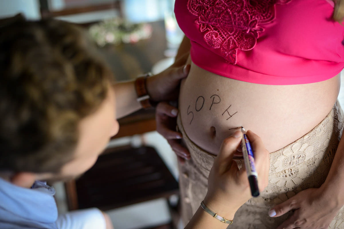 Ensaio de casal gestante em casa com cachorro fotografado pelo melhor fotógrafo de casamentos e ensaios de campo largo e Curitiba, Michel Druziki. Noivo escrevendo nome Sophia na barriga da noiva grávida