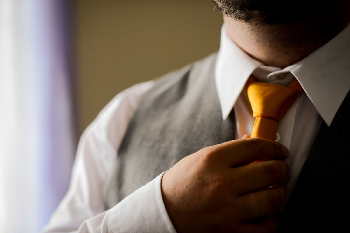 Casamento ao ar livre e de dia dos noivos Kelly e Flávio fotografado pelo melhor fotógrafo de Campo Largo e região de Curitiba, Michel Druziki. Noivo arrumando a gravata. Gravata amarela