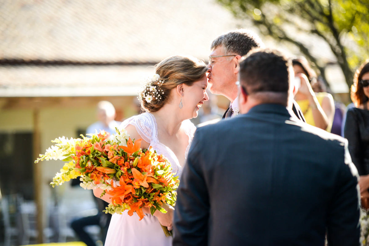 Casamento ao ar livre e de dia dos noivos Kelly e Flávio fotografado pelo melhor fotógrafo de Campo Largo e região de Curitiba, Michel Druziki. Pai da noiva dando beijo na testa