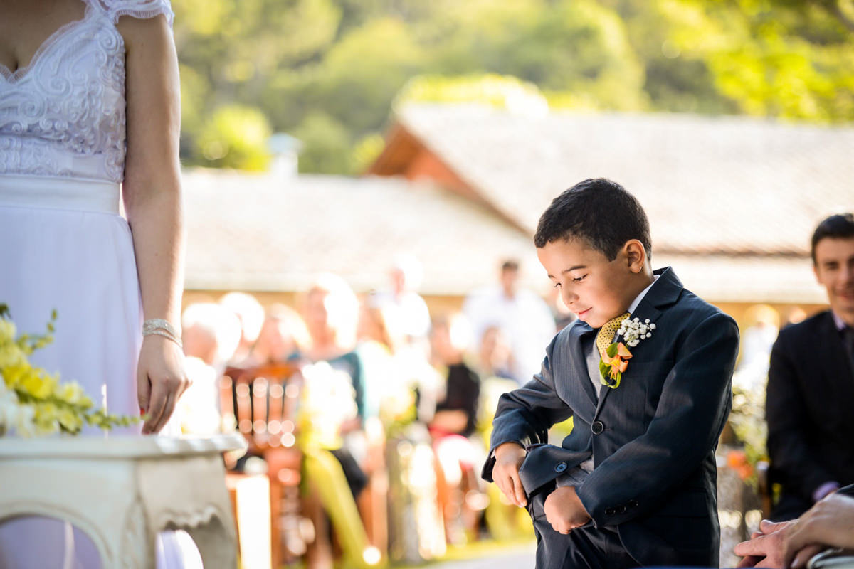 Casamento ao ar livre e de dia dos noivos Kelly e Flávio fotografado pelo melhor fotógrafo de Campo Largo e região de Curitiba, Michel Druziki. Pagem tirando as alianças do bolso