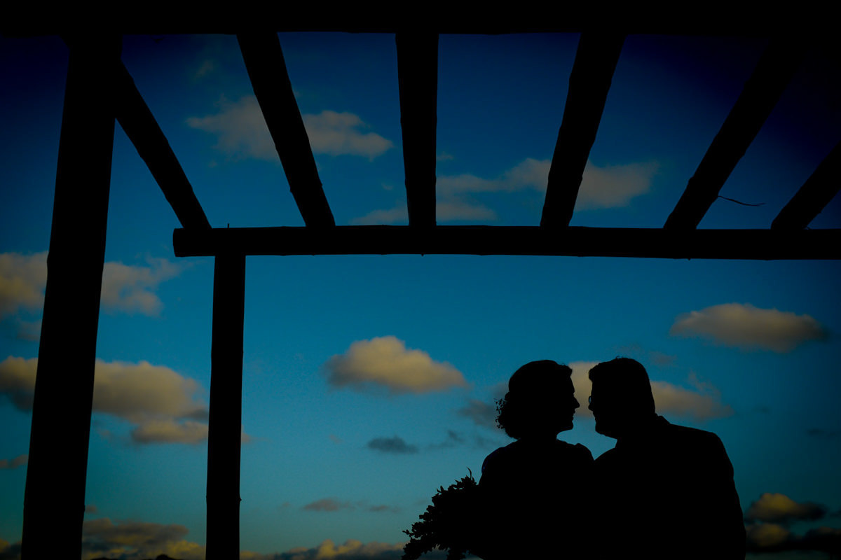 Casamento ao ar livre e de dia dos noivos Kelly e Flávio fotografado pelo melhor fotógrafo de Campo Largo e região de Curitiba, Michel Druziki. Silhueta dos noivos abraçados e sorrindo