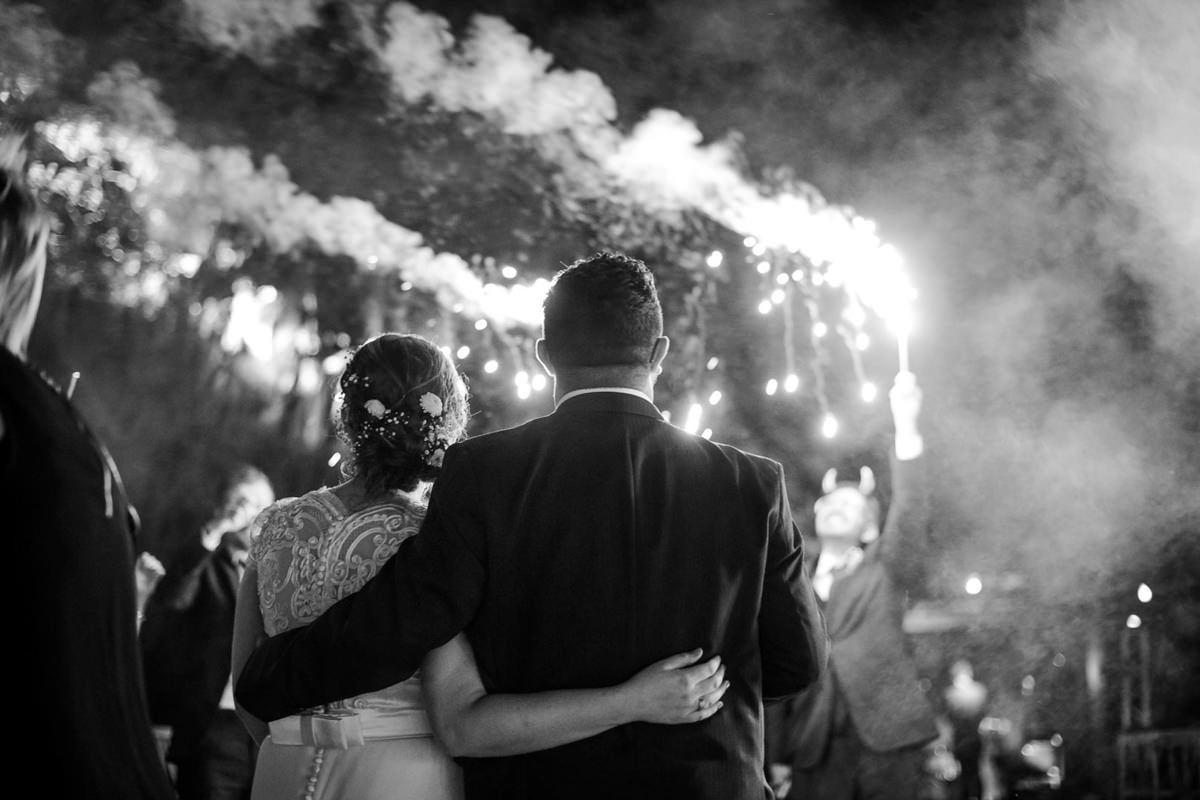 Casamento ao ar livre e de dia dos noivos Kelly e Flávio fotografado pelo melhor fotógrafo de Campo Largo e região de Curitiba, Michel Druziki. Noivos abraçados olhando os fogos de artifício