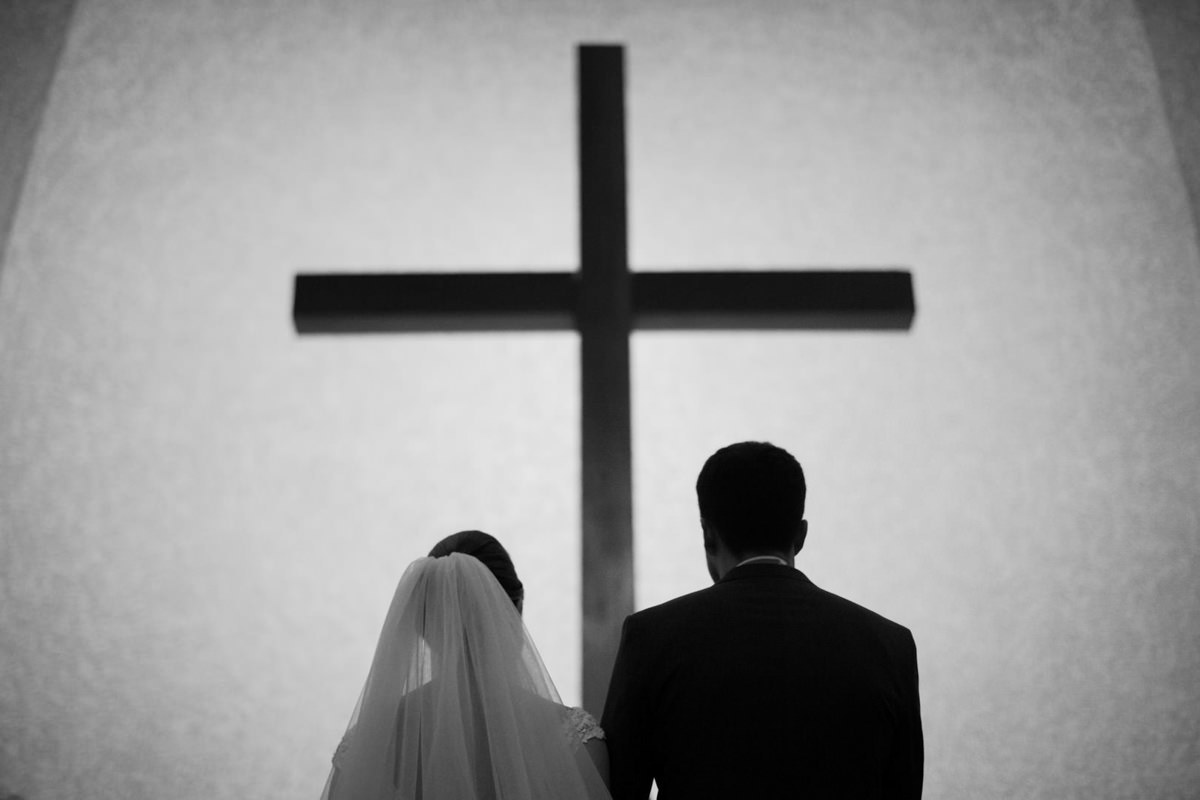 Casamento dos noivos Nayara e Emílio, fotografado pelo fotógrafo de ensaios e casamento em Campo Largo e Curitiba, Michel Druziki. Silhueta dos noivos e da cruz