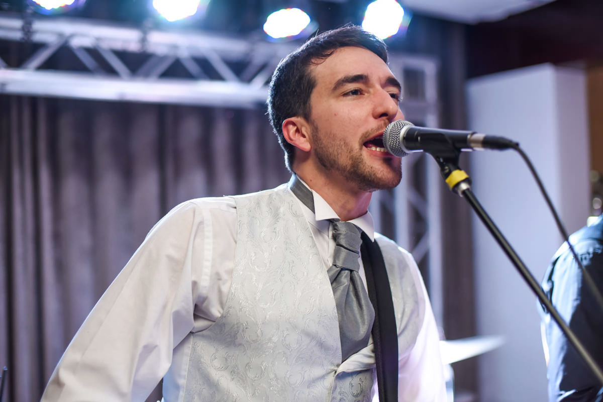 Casamento dos noivos Nayara e Emílio, fotografado pelo fotógrafo de ensaios e casamento em Campo Largo e Curitiba, Michel Druziki. Noivo cantando durante a festa