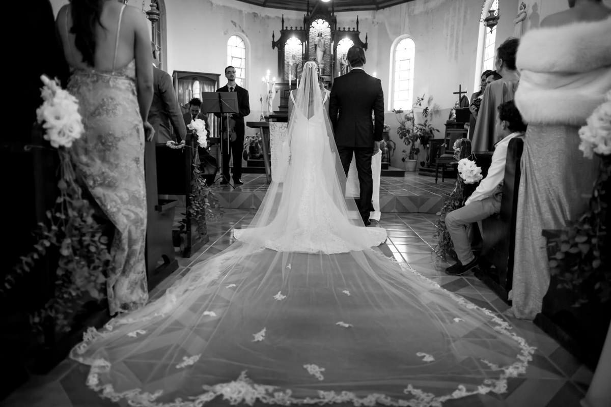 Casamento dos noivos Neriane e Eduardo fotografado pelo melhor fotógrafo de casamentos e ensaios de campo largo e Curitiba, Michel Druziki. Noivos no altar. Véu da noiva bem grande na igreja