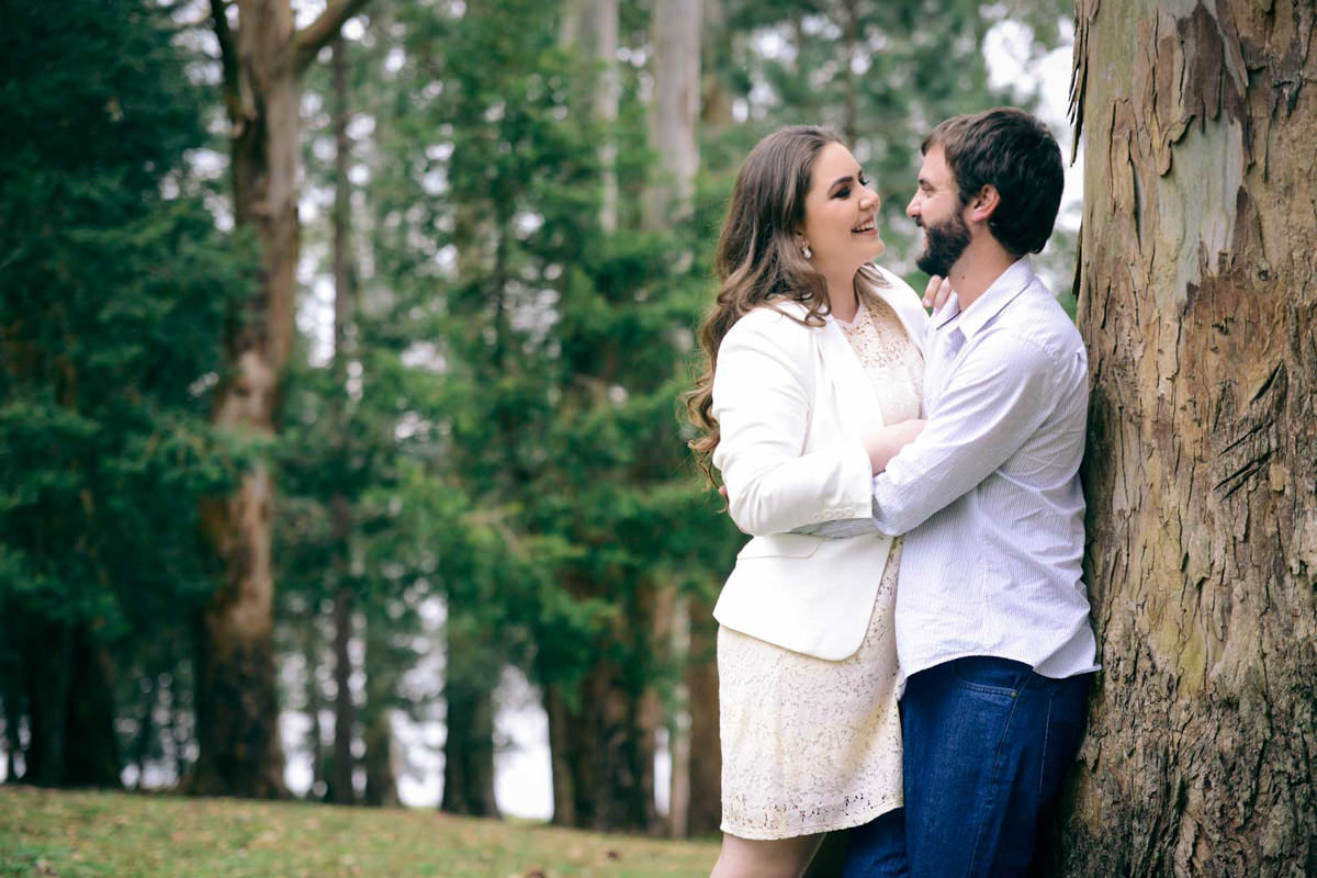 Pre wedding no campo do casal Nicole e Alisson fotografado pelo melhor fotógrafo de casamentos de campo largo e Curitiba, Michel Druziki. Casal sorrindo abraçado e encostado na árvore