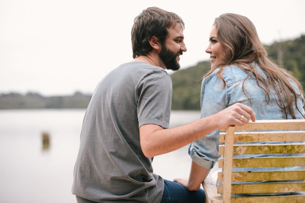 Pre wedding no campo do casal Nicole e Alisson fotografado pelo melhor fotógrafo de casamentos de campo largo e Curitiba, Michel Druziki. Noiva sentada no banco e olhando para o noivo