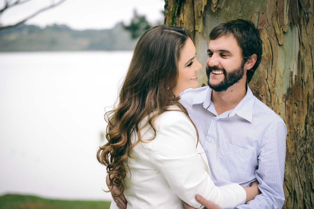 Pre wedding no campo do casal Nicole e Alisson fotografado pelo melhor fotógrafo de casamentos de campo largo e Curitiba, Michel Druziki. Noivos sorrindo encostados na árvore.