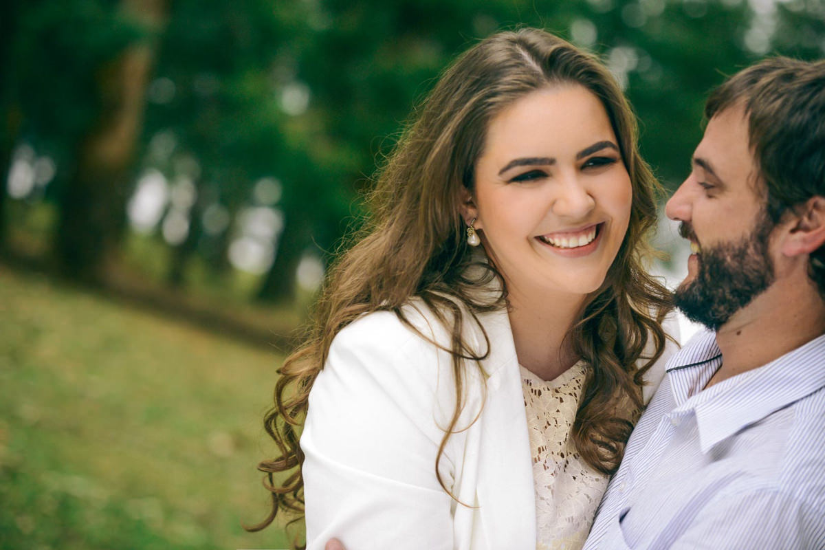 Pre wedding no campo do casal Nicole e Alisson fotografado pelo melhor fotógrafo de casamentos de campo largo e Curitiba, Michel Druziki. Noivos sorrindo encostados na árvore.