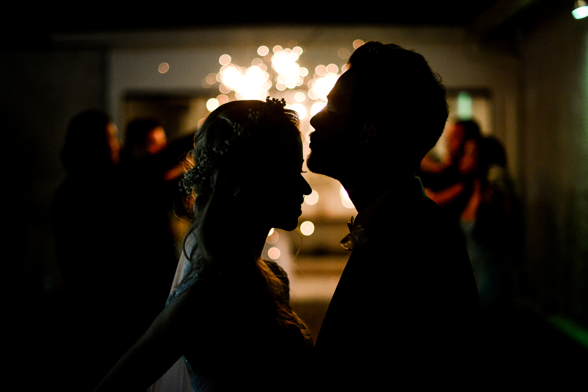 Casamento dos noivos Roxanne e Diego fotografado pelo melhor fotógrafo de Campo Largo e região de Curitiba, Michel Druziki. Silhueta dos noivos e ao fundo luzes das velas estrelas de prata