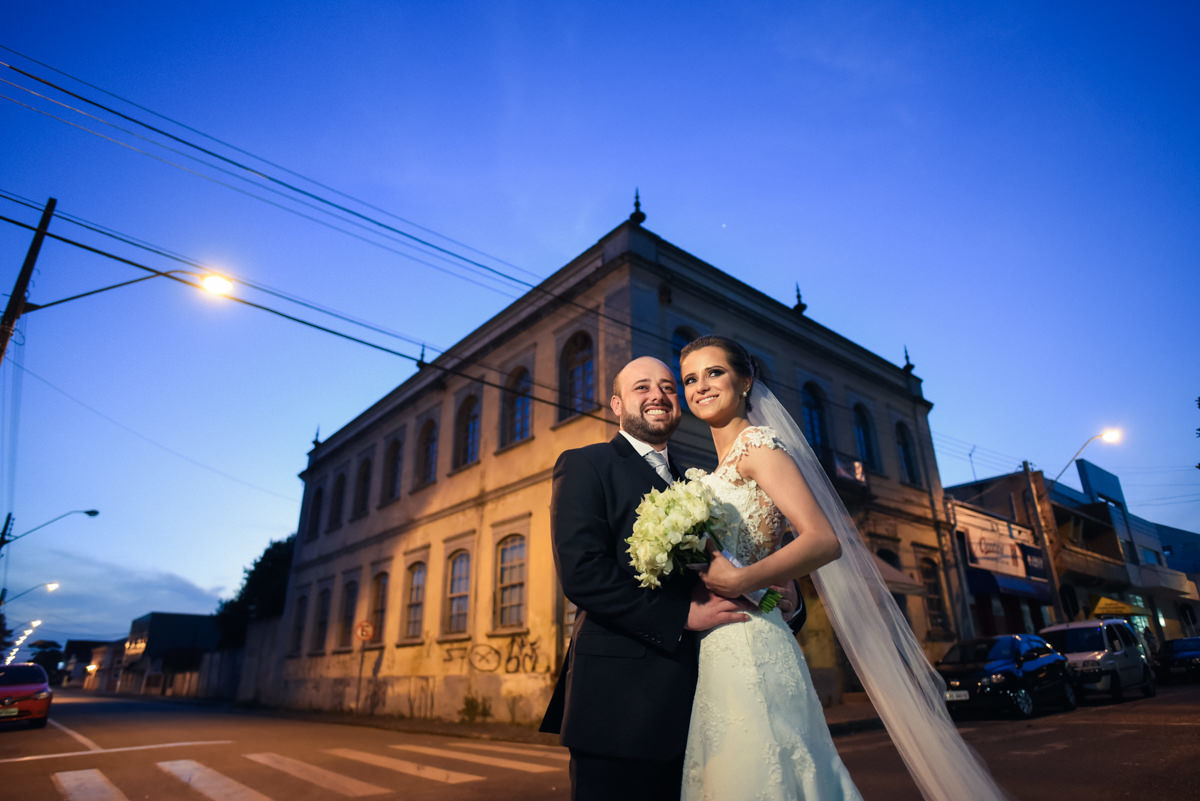 Casamento dos queridos Larissa e Cícero fotografado pelo melhor fotógrafo de casamentos de campo largo e Curitiba, Michel Druziki. Noivos abraçados e sorrindo na rua depois do casamento, céu azul