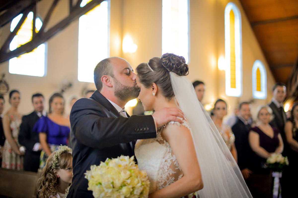 Casamento dos queridos Larissa e Cícero fotografado pelo melhor fotógrafo de casamentos de campo largo e Curitiba, Michel Druziki. Noivo beijando testa da noiva no altar