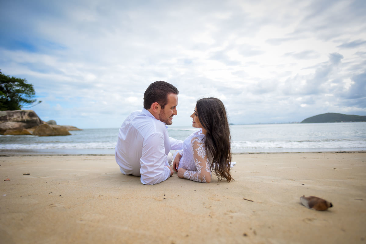 Ensaio de casamento na praia dos noivos Bruna e Jefferson fotografado pelo fotógrafo de Campo Largo e Curitiba, Michel Druziki. Noivos deitados na areia se olhando