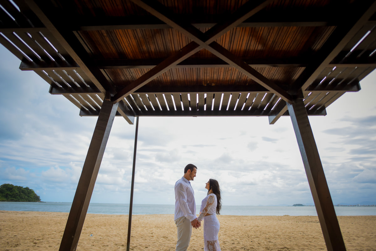 Ensaio de casamento na praia dos noivos Bruna e Jefferson fotografado pelo fotógrafo de Campo Largo e Curitiba, Michel Druziki. Noivos de mãos dadas se olhando na areia
