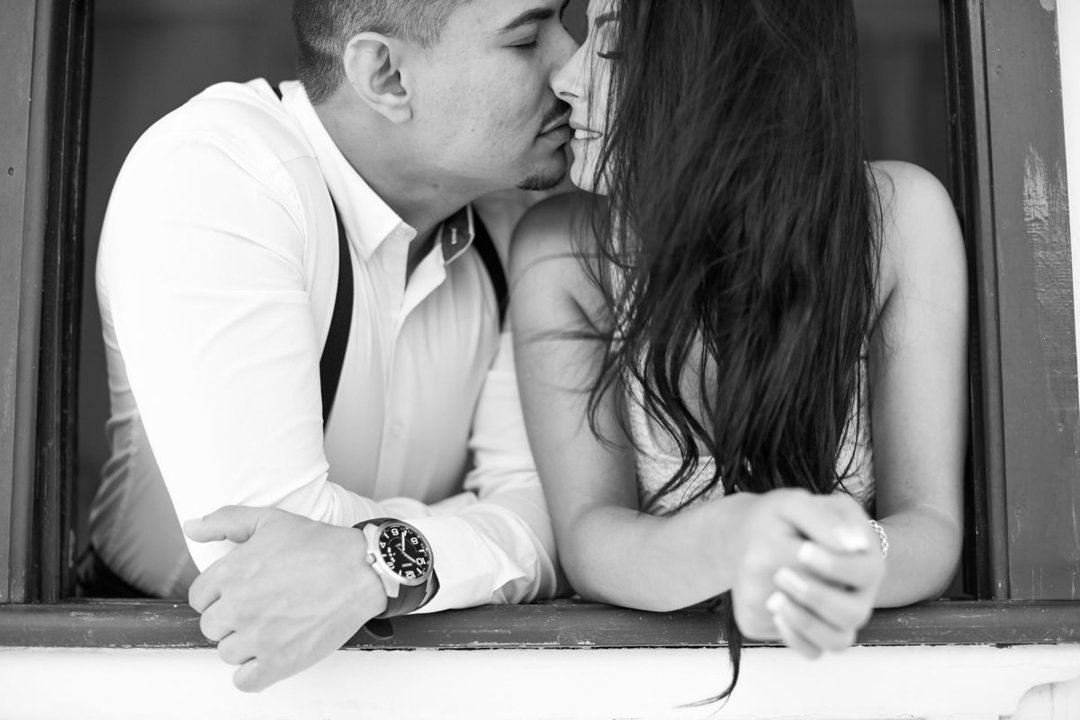 Ensaio do casal Letícia e Rodrigo em casa fotografado pelo melhor fotógrafo de casamentos e ensaios de campo largo e Curitiba, Michel Druziki. Casal se beijando na janela