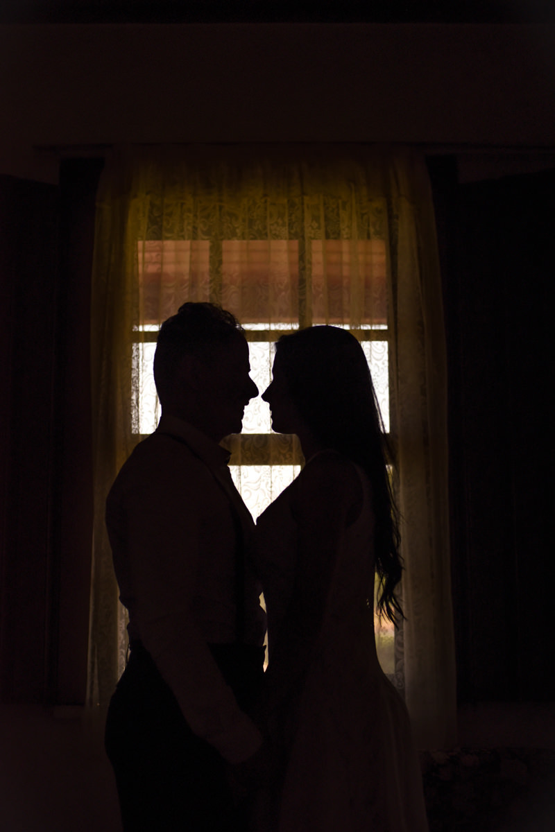 Ensaio do casal Letícia e Rodrigo em casa fotografado pelo melhor fotógrafo de casamentos e ensaios de campo largo e Curitiba, Michel Druziki. Silhueta dos noivos em frente à janela