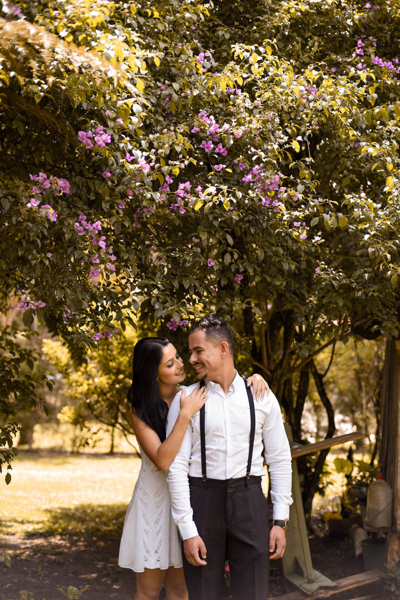 Ensaio do casal Letícia e Rodrigo em casa fotografado pelo melhor fotógrafo de casamentos e ensaios de campo largo e Curitiba, Michel Druziki. Noiva atrás do noivo sorrindo embaixo da árvore sorrindo