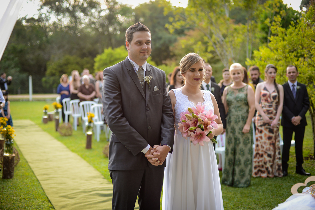Casamento de dia ao ar livre dos noivos Cheila e Lúcio, no Negrão Eventos, fotografado pelo melhor fotógrafo de casamentos de campo largo e Curitiba, Michel Druziki. Noivos de mãos dadas durante a cerimônia