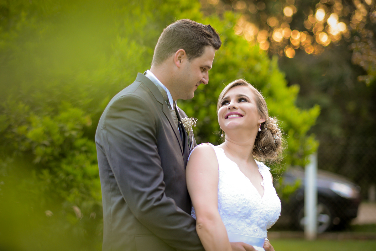 Casamento de dia ao ar livre dos noivos Cheila e Lúcio, no Negrão Eventos, fotografado pelo melhor fotógrafo de casamentos de campo largo e Curitiba, Michel Druziki. Noivos abraçados se olhando e sorrindo