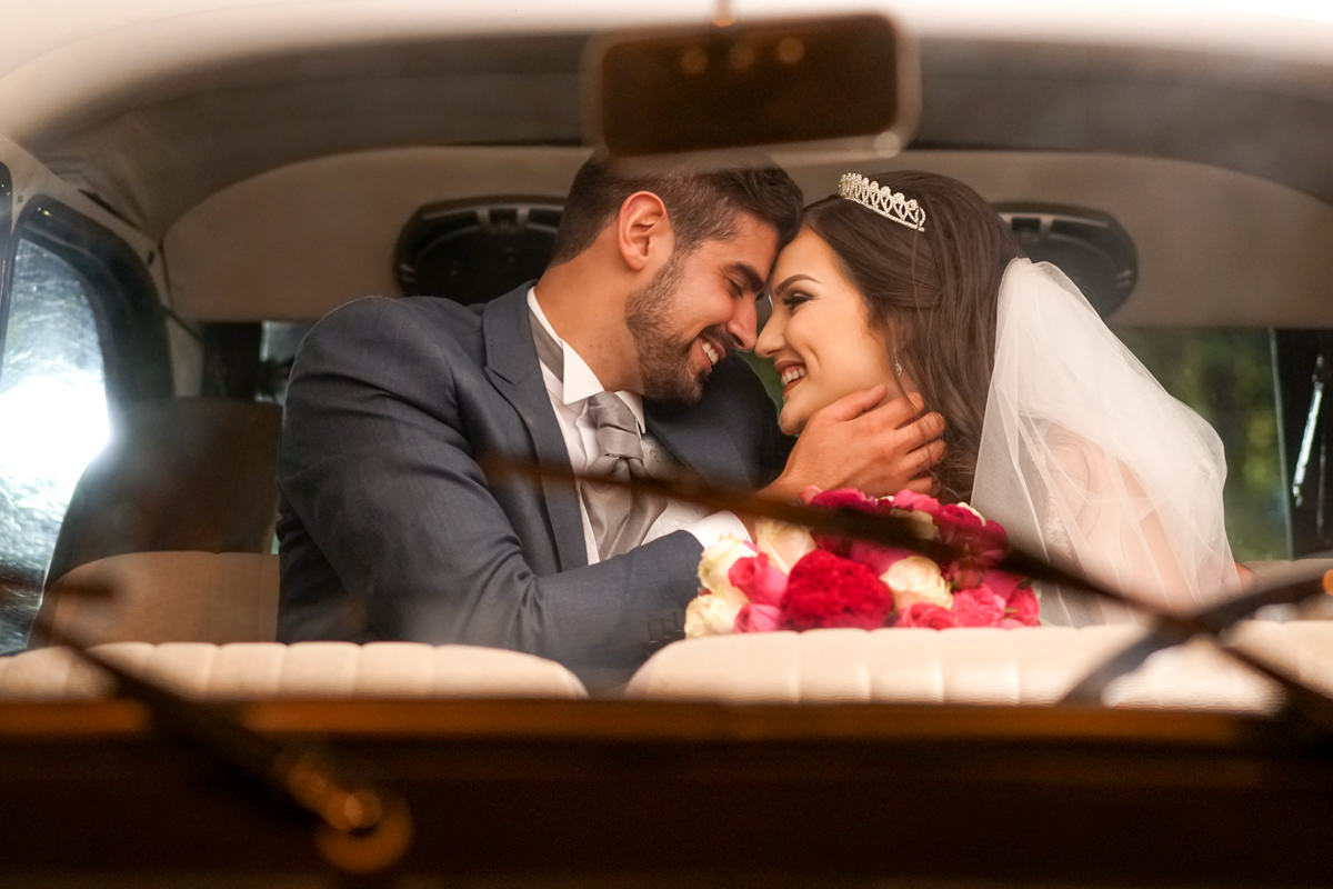  O fotógrafo de casamentos Michel Druziki, fotografou o casamento lindo do casal Gisele e Vinícius na cidade de Campo Largo. Noivos sorrindo dentro do carro depois do casamento
