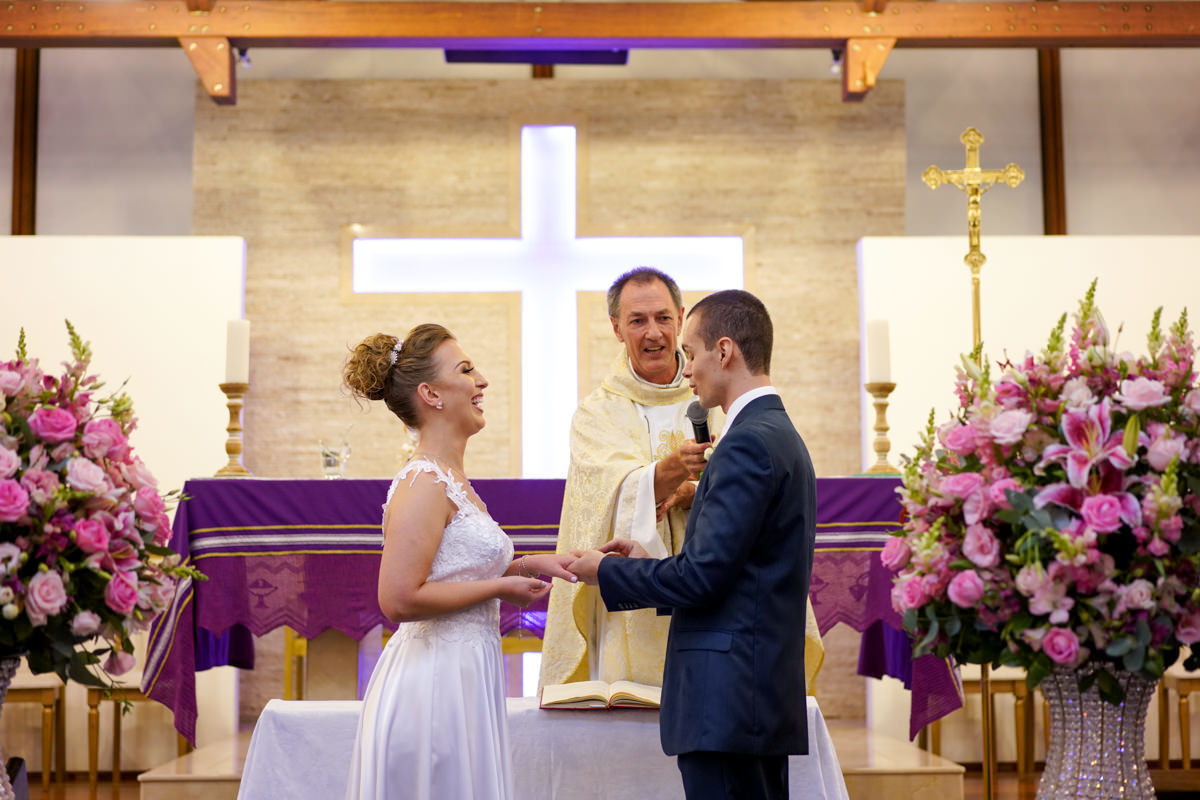 Casamento dos noivos Francine e Rodrigo realizado em Curitiba, com festa no restaurante Madalosso, fotografado pelo melhor fotógrafo de casamentos de Campo Largo e Curitiba, Michel Druziki. Noivos sorrindo durante a troca de alianças