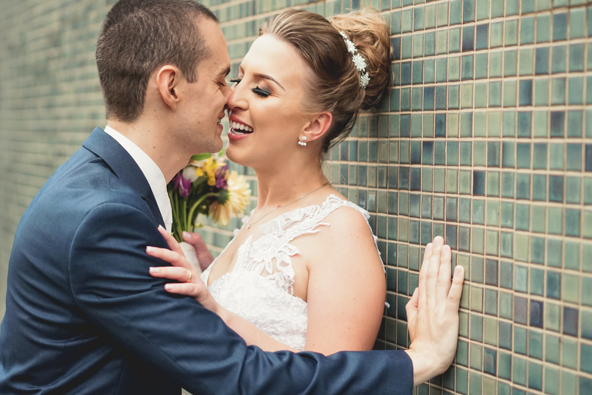 Casamento dos noivos Francine e Rodrigo realizado em Curitiba, com festa no restaurante Madalosso, fotografado pelo melhor fotógrafo de casamentos de Campo Largo e Curitiba, Michel Druziki. Noivos sorrindo encostados na parede 