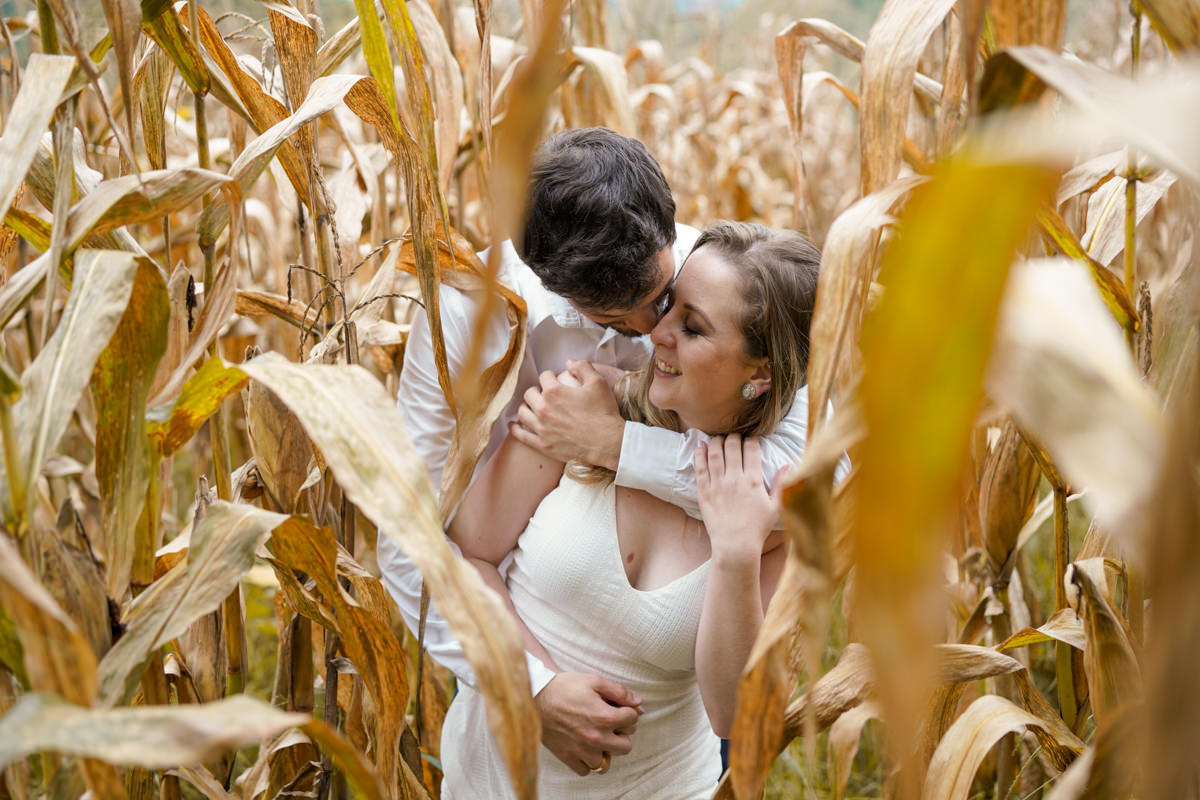 Ensaio de casamento do casal Camila e Guto fotografado pelo fotógrafo Michel Druziki em Campo Largo. Noivos abraçados e sorrindo no milharal