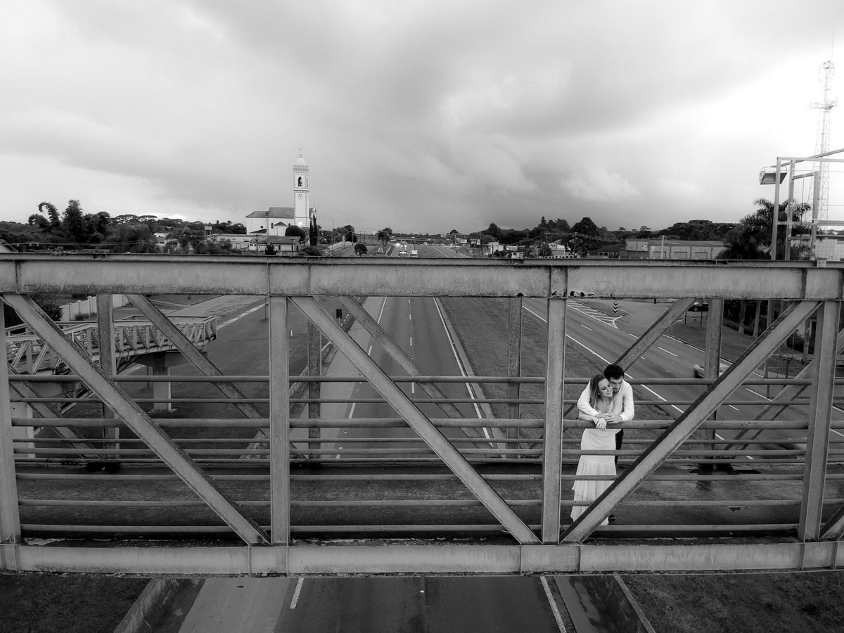 Ensaio de casamento do casal Camila e Guto fotografado pelo fotógrafo Michel Druziki em Campo Largo. Noivos abraçados e fotografados com drone em cima da passarela