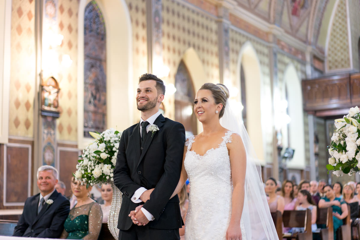 Casamento da Camila e Guto na igreja Matriz de Campo Largo, fotografado pelo melhor fotógrafo de casamentos em Campo Largo e Curitiba, Michel Druziki. Noivos sorrindo e de mãos dadas durante a cerimônia 
