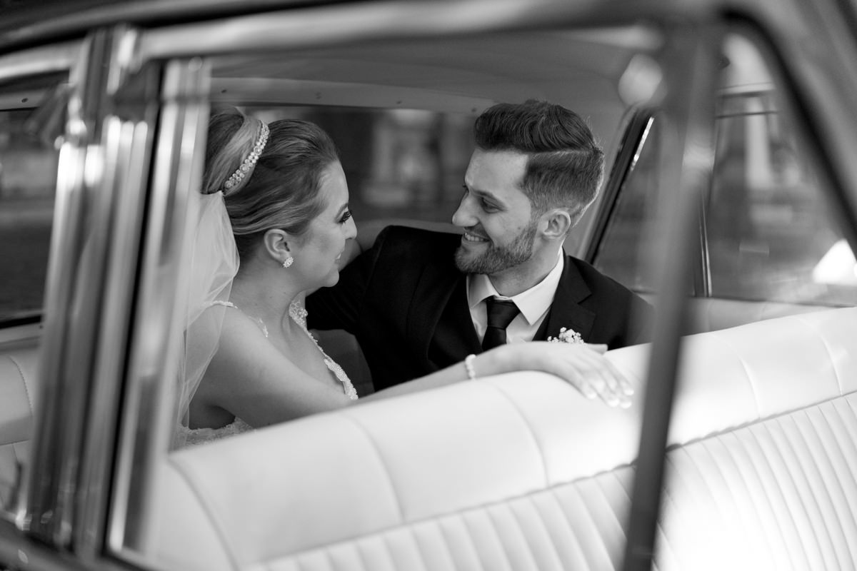 Casamento da Camila e Guto na igreja Matriz de Campo Largo, fotografado pelo melhor fotógrafo de casamentos em Campo Largo e Curitiba, Michel Druziki. Noivos dentro do carro se olhando e sorrindo após o casamento