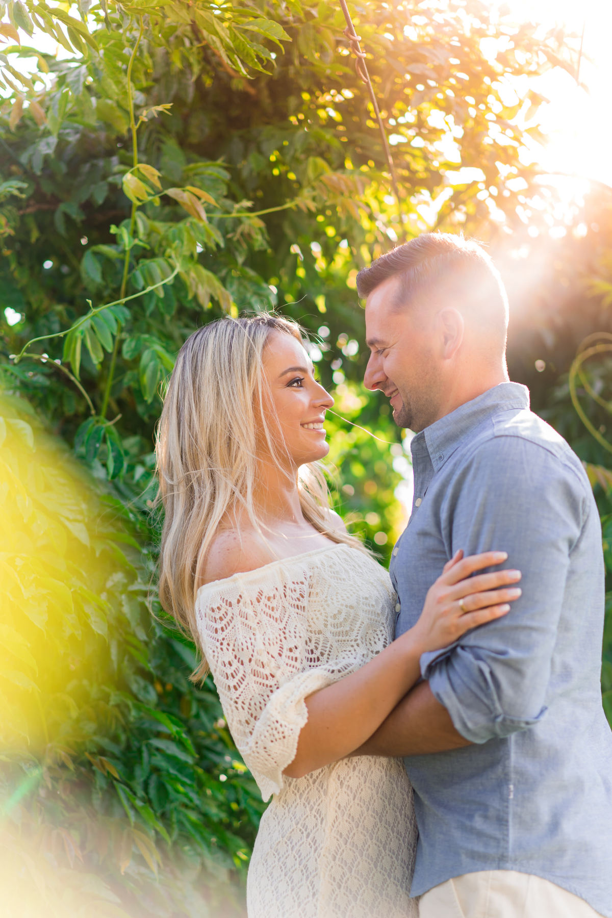 Casal abraçado sorrindo com um raio de sol.