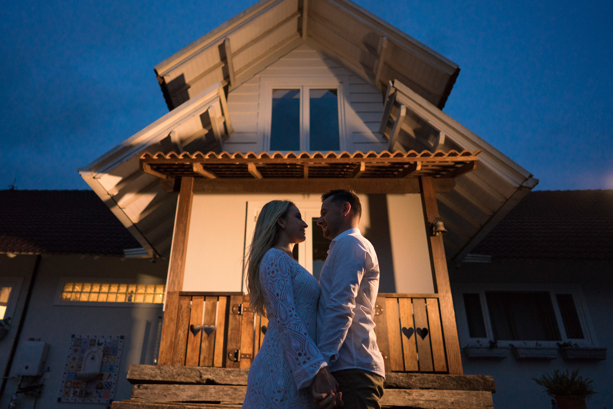 O fotógrafo de casamentos em Campo Largo e Curitiba, Michel Druziki fotografou o casal Ana Maria e Ricardo no Rancho P&R Luxo do Campo em São Luiz do Purunã. Casal de mãos dadas em frente à casa no começo da noite.