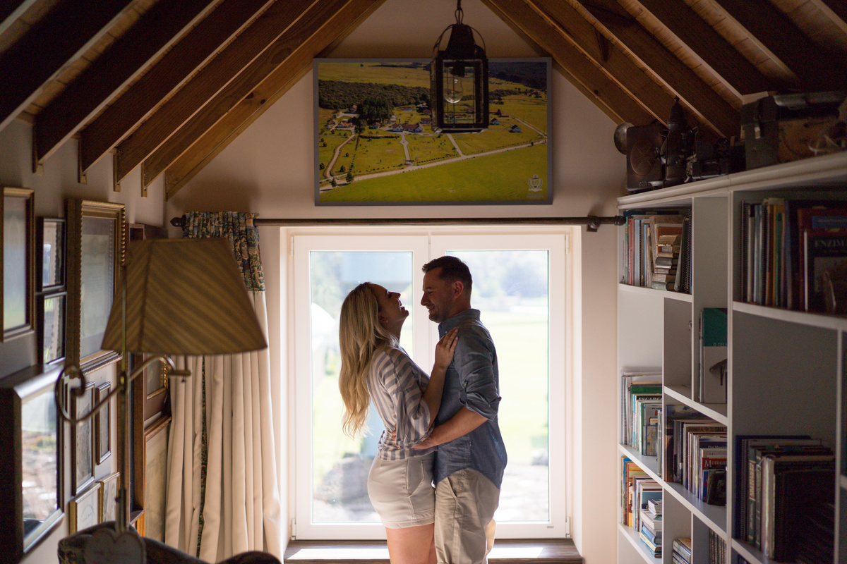 O fotógrafo de casamentos em Campo Largo e Curitiba, Michel Druziki fotografou o casal Ana Maria e Ricardo no Rancho P&R Luxo do Campo em São Luiz do Purunã. Casal na janela abraçados, sorrindo.